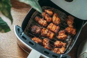 Crispy seasoned chicken pieces on a rack inside an open air fryer basket