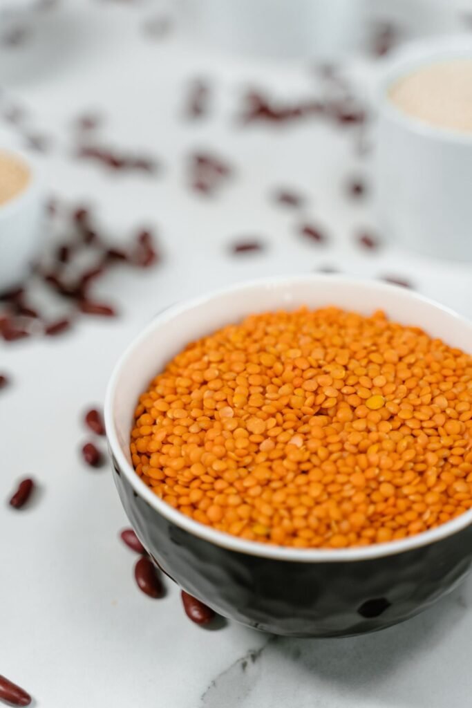 Raw red lentils in a white ceramic bowl on a kitchen counter