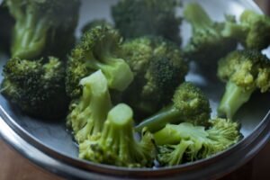 Freshly steamed broccoli florets in a stainless steel pot